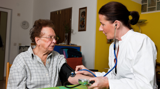 doctor checking the elder woman's blood pressure