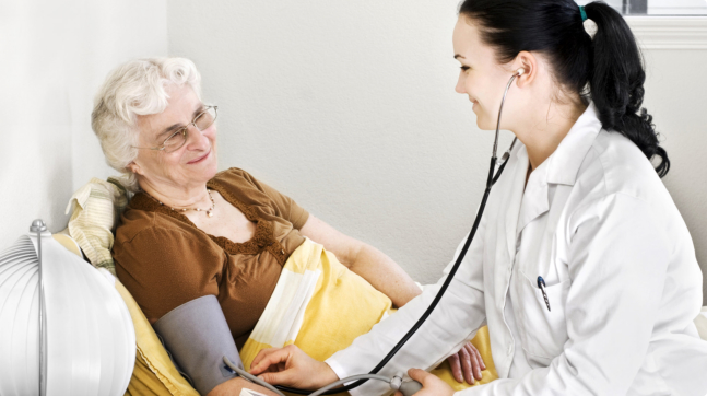 doctor checking the elder woman's blood pressure on the bed