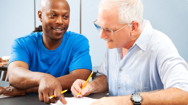 caregiver assisting the elder man on filling up the documents